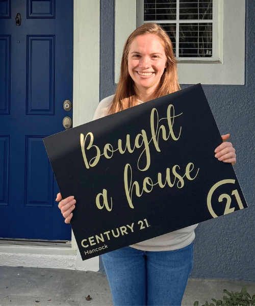 Woman found home for sale in clermont fl and holding up a sign that says bought a house