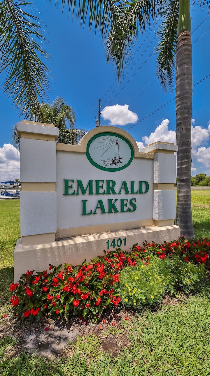 Neighborhood entrance sign featuring a lighthouse logo for Emerald Lakes Co-Op, a 55+ community in Clermont, Florida.
